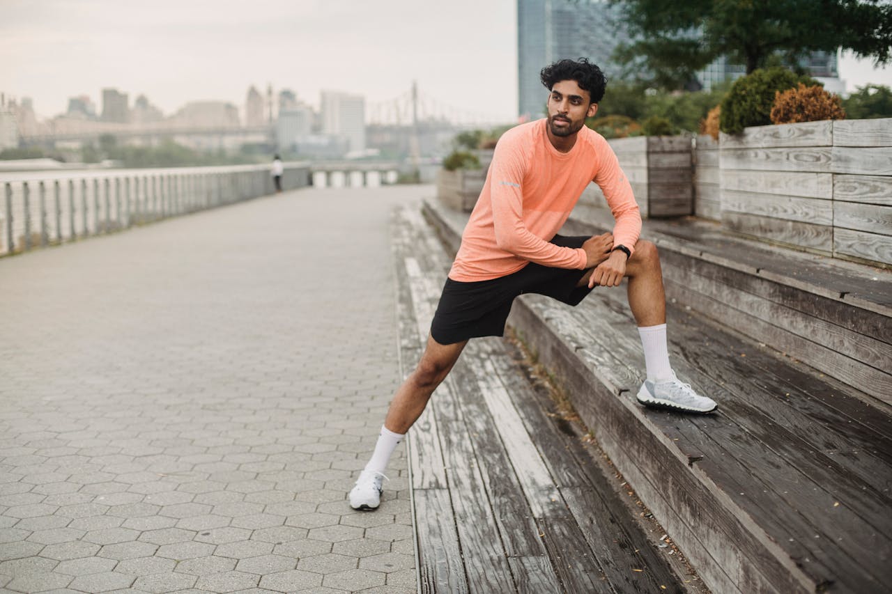A man stretches on a riverside promenade, embracing fitness and an active lifestyle.